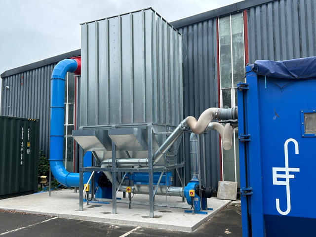 A rotary valve filter placed behind a building and connected to a container